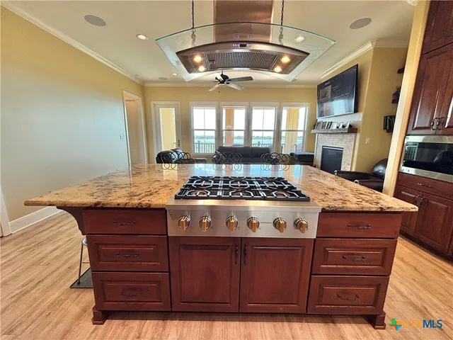 a view of a kitchen with kitchen island wooden floors stainless steel appliances