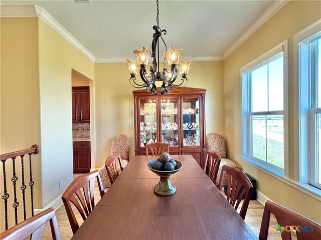 a view of a dining room with furniture a chandelier and large windows