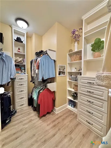 a view of walk in closet with clothes and shoes