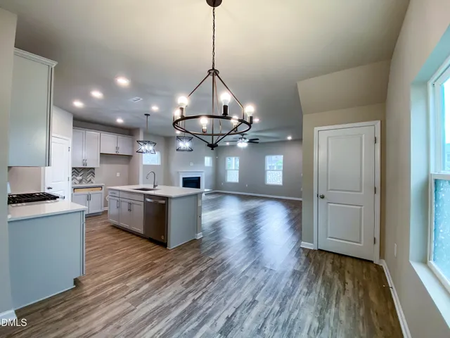 a view of a kitchen with a sink dishwasher and a fireplace with wooden floor