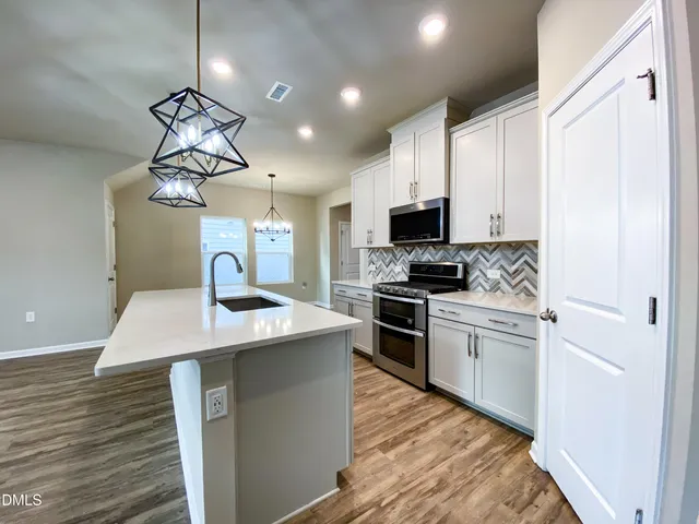 a view of a livingroom with a chandelier fan and windows