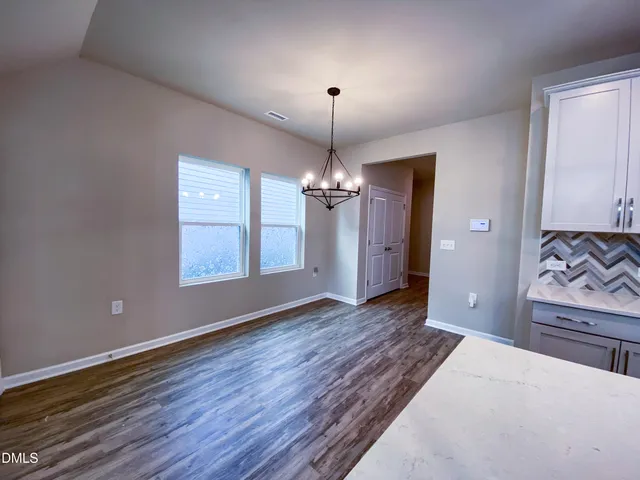 an empty room with windows and chandelier fan