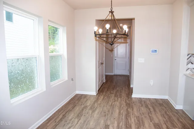 an empty room with windows and a chandelier fan