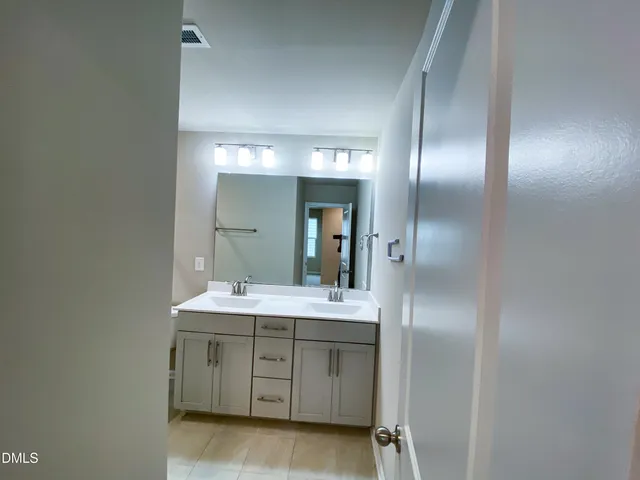 a spacious bathroom with a double vanity sink and mirror