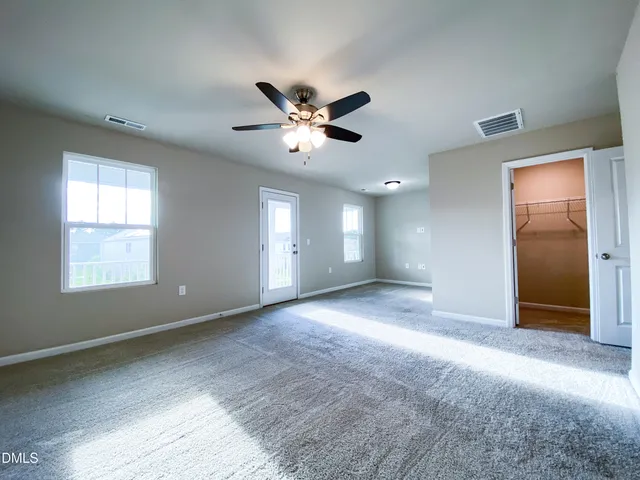 an empty room with windows and fan