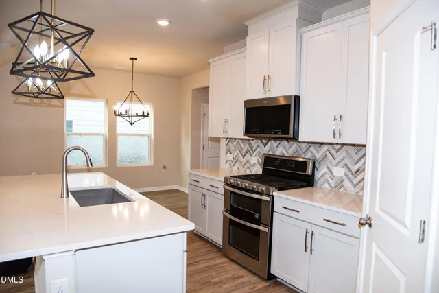 a large kitchen with kitchen island a stove a sink a refrigerator and white cabinets
