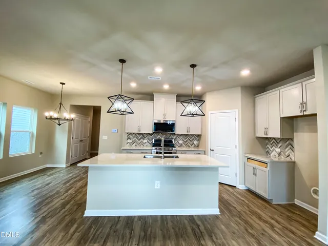 a kitchen with kitchen island granite countertop a sink cabinets and wooden floor