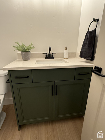 658 West 500 South, Unit 2 Logan, UT 84321 - Photo 13 of 18 Green vanity with black hardware, white rectangular basin, light-colored countertop, and wood-finish flooring