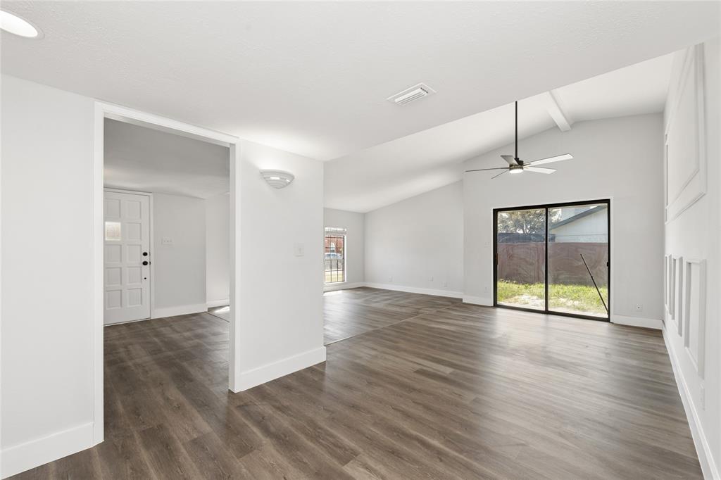2119 Meadfoot Road Carrollton, TX 75007 - Photo 6 of 30 Unfurnished room featuring dark wood-type flooring, healthy amount of natural light, lofted ceiling, and a ceiling fan