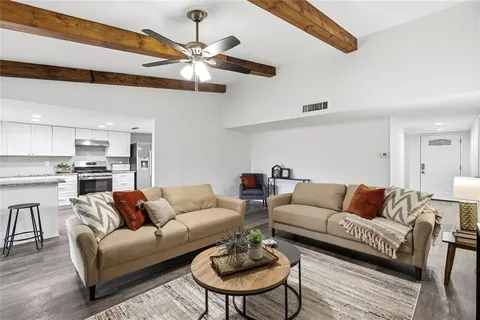 a living room with furniture kitchen view and a chandelier