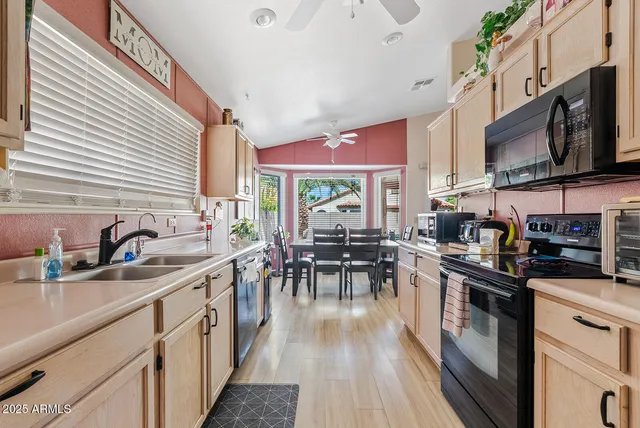 a kitchen with stainless steel appliances a stove top oven a sink dishwasher a dining table and chairs with wooden floor