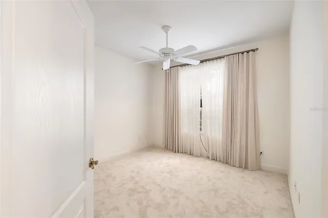 an empty room with a ceiling fan and a window