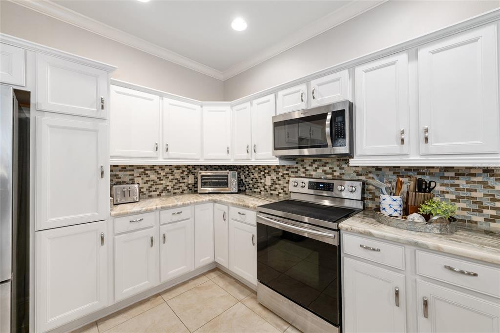 879 Chapman Loop The Villages, FL 32162 - Photo 7 of 34 a kitchen with white cabinets and white appliances