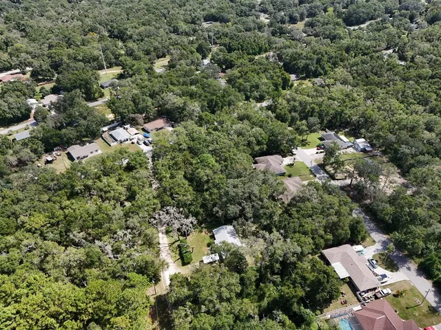 an aerial view of residential house with outdoor space and trees all around