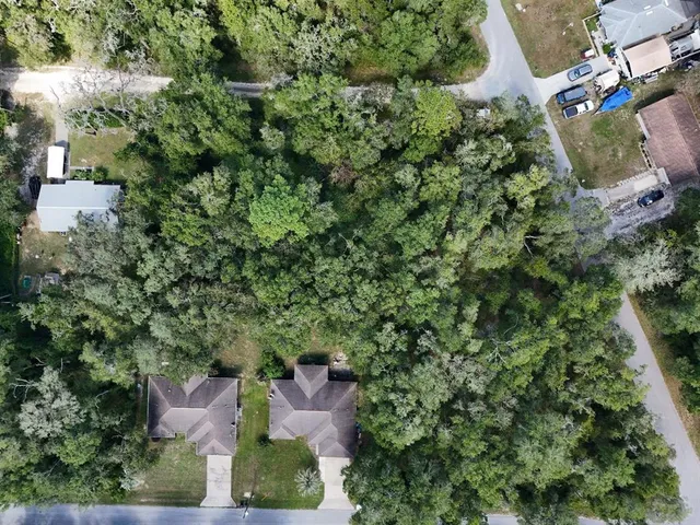an aerial view of residential house with outdoor space and trees all around