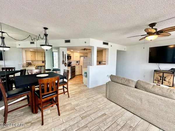 a living room with furniture a flat screen tv and kitchen view