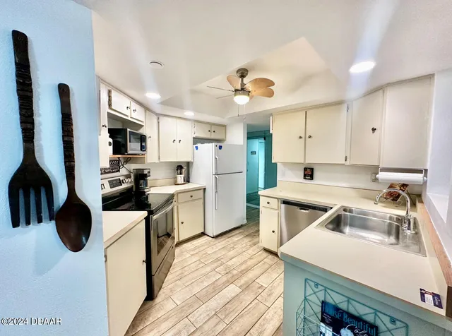 a kitchen with stainless steel appliances a stove a sink a refrigerator and chairs