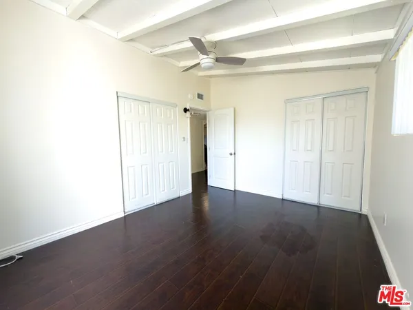 an empty room with wooden floor and a ceiling fan