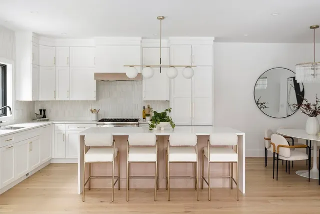 a kitchen with a dining table chairs and white cabinets