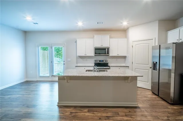 a kitchen with stainless steel appliances granite countertop a refrigerator a stove top oven a sink and dishwasher with wooden floor