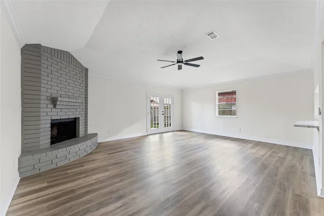 a view of an empty room with wooden floor fireplace and a window