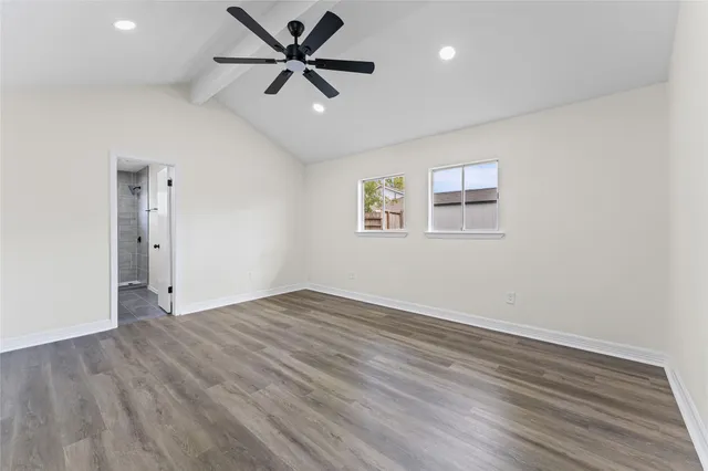 an empty room with wooden floor ceiling fan and windows
