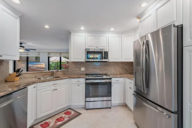 a kitchen with stainless steel appliances granite countertop a refrigerator sink and stove