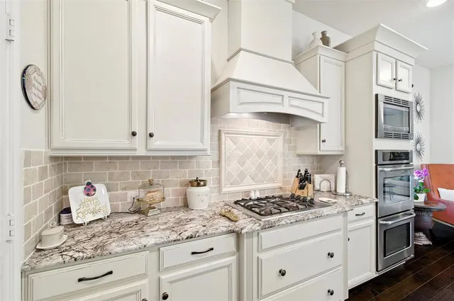 a kitchen with granite countertop white cabinets and stainless steel appliances