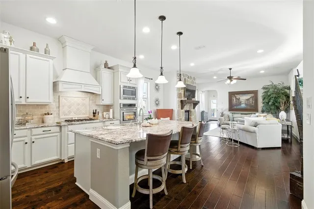 a kitchen with stainless steel appliances kitchen island granite countertop a stove a sink dishwasher and a dining table with wooden floor