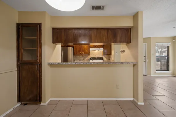 a view of a refrigerator in kitchen and an empty room