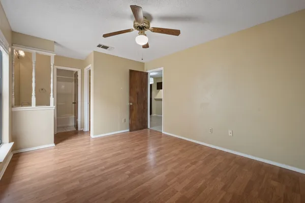 an empty room with wooden floor and a ceiling fan