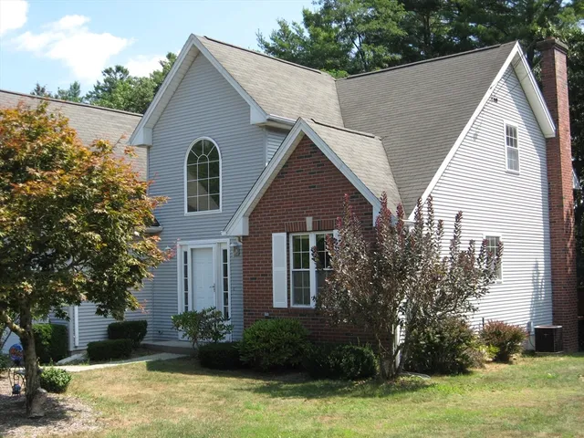 a view of a white house next to a yard with large trees