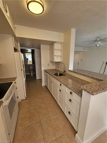 a kitchen with granite countertop a sink a stove and a refrigerator