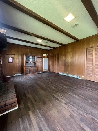 a view of an empty room with window and wooden floor