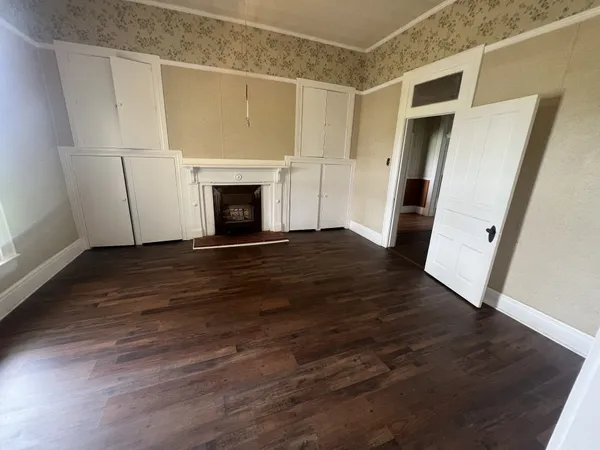 a view of a livingroom with wooden floor and a fireplace