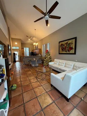 a living room with couches and kitchen view with wooden floor