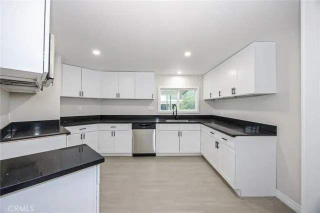 a kitchen with granite countertop a sink a stove and cabinets
