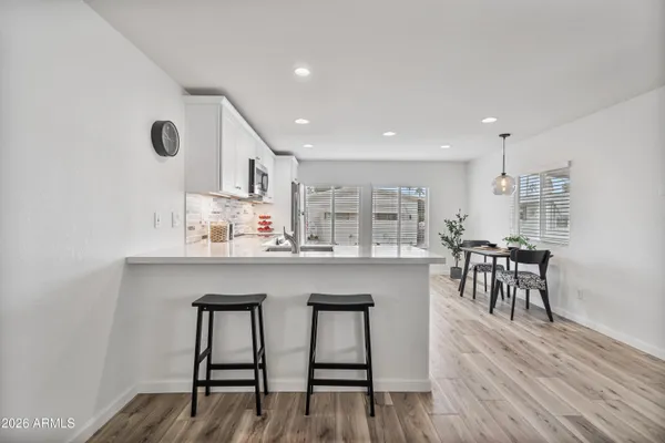 a kitchen with stainless steel appliances kitchen island hardwood floor sink stove dining table and chairs