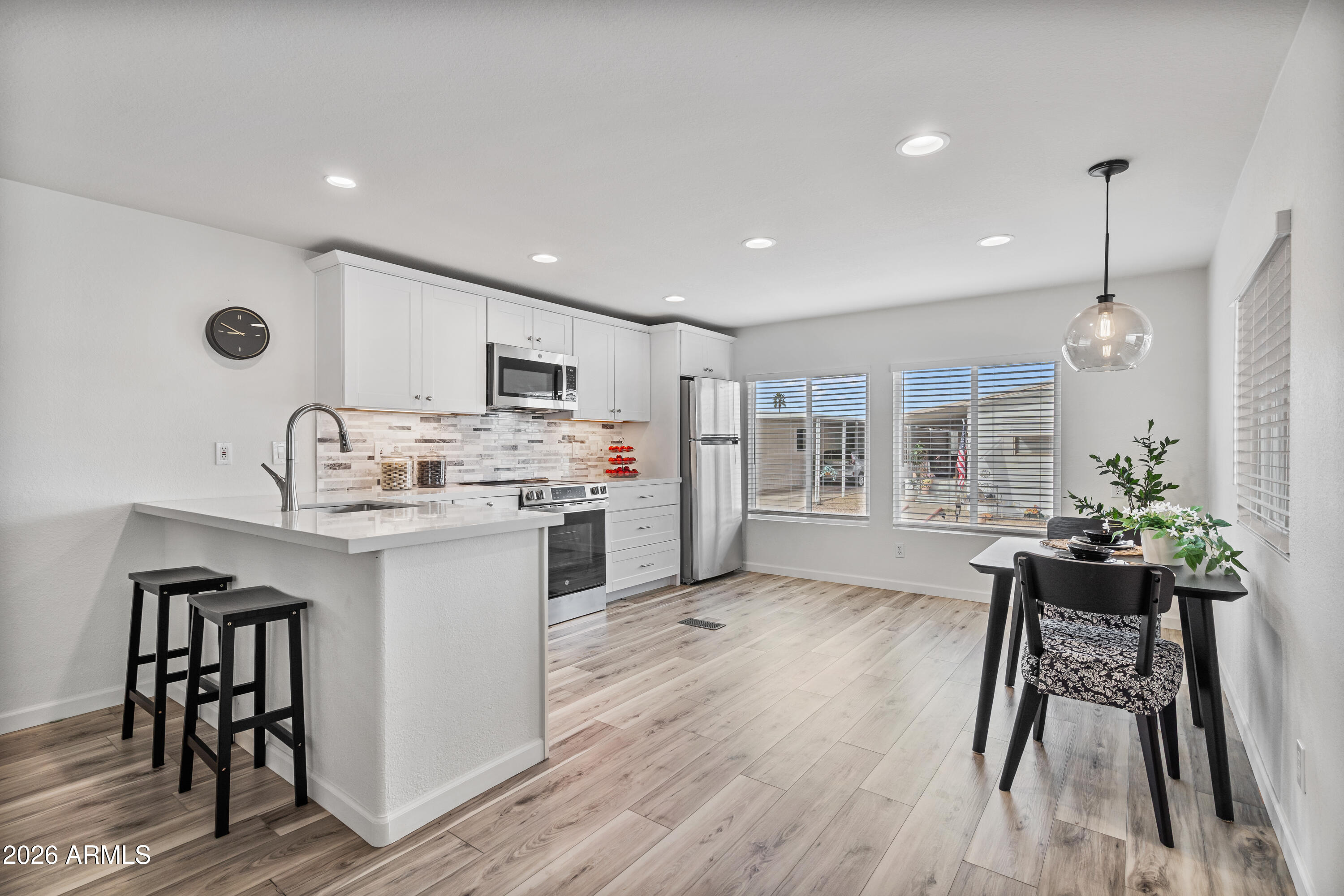205 South Higley Road, Unit 52 Mesa, AZ 85206 - Photo 15 of 34 a kitchen with stainless steel appliances kitchen island hardwood floor sink stove dining table and chairs