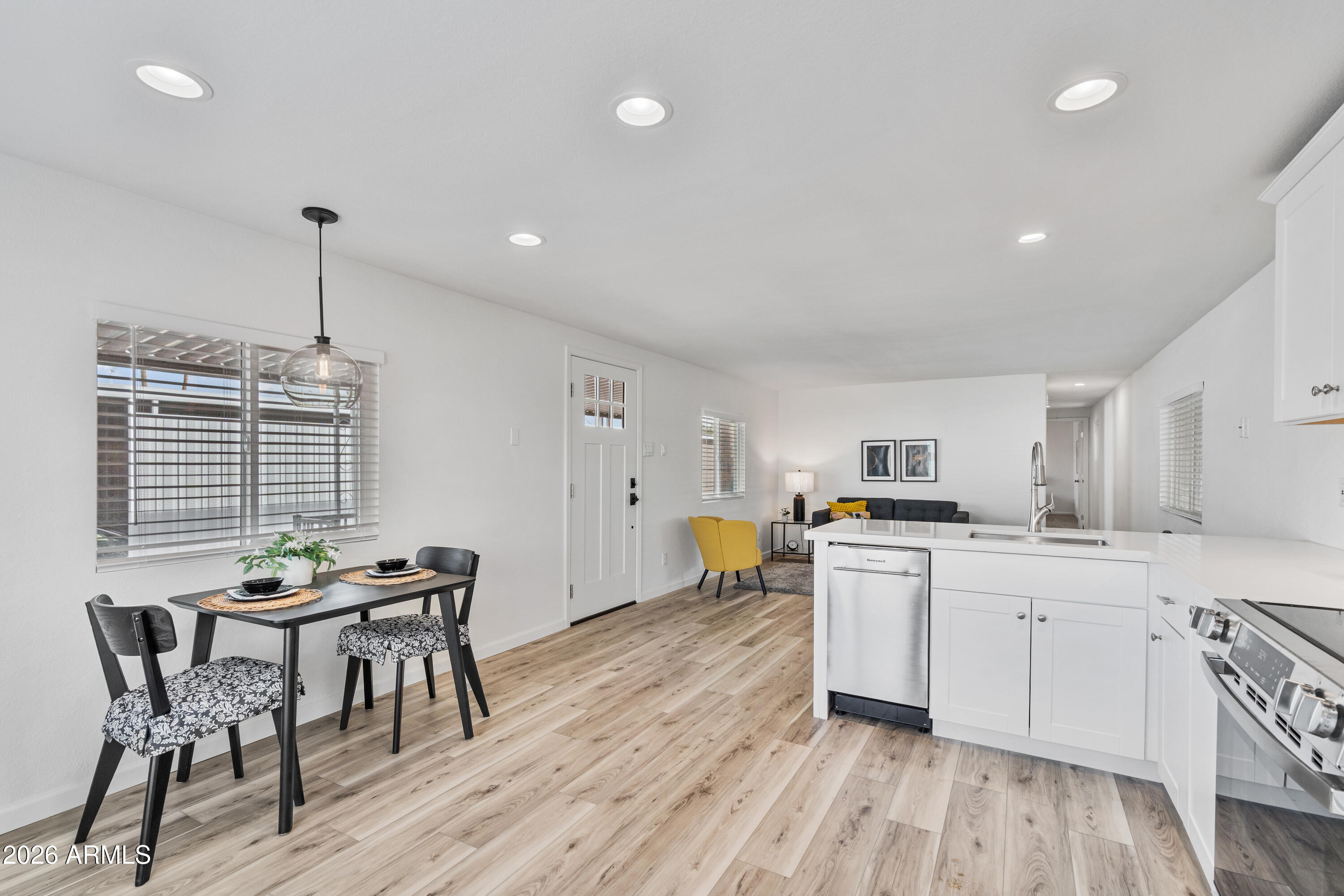 205 South Higley Road, Unit 52 Mesa, AZ 85206 - Photo 16 of 34 a kitchen with stainless steel appliances a white table chairs and wooden floor