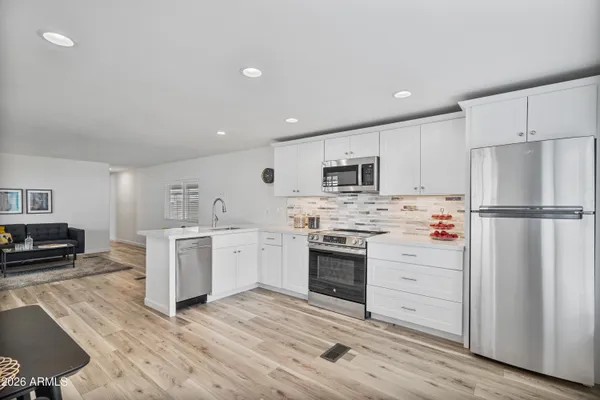 a kitchen with cabinets stainless steel appliances and wooden floor