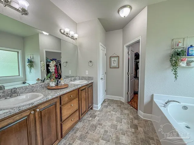 a spacious bathroom with a granite countertop sink a toilet a mirror a bathtub and shower