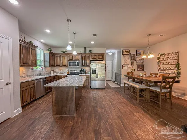 a kitchen with stainless steel appliances kitchen island granite countertop wooden floors and view living room