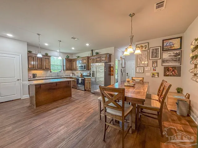 a view of a dining room and livingroom with furniture wooden floor a chandelier