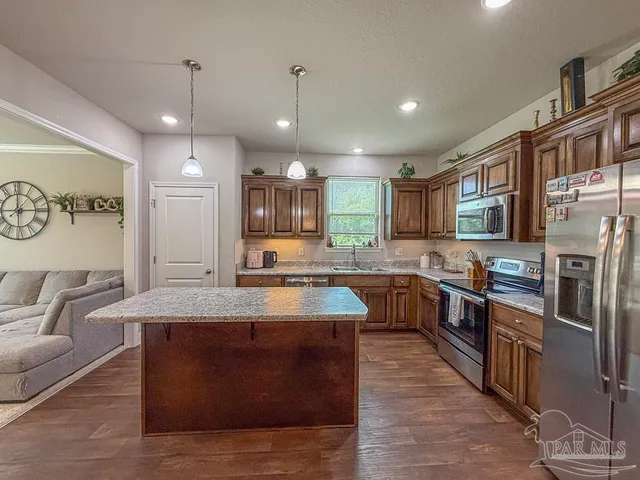 a large kitchen with stainless steel appliances kitchen island granite countertop a sink counter space and a center island