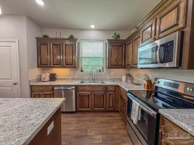 a kitchen with stainless steel appliances granite countertop a stove sink microwave and cabinets