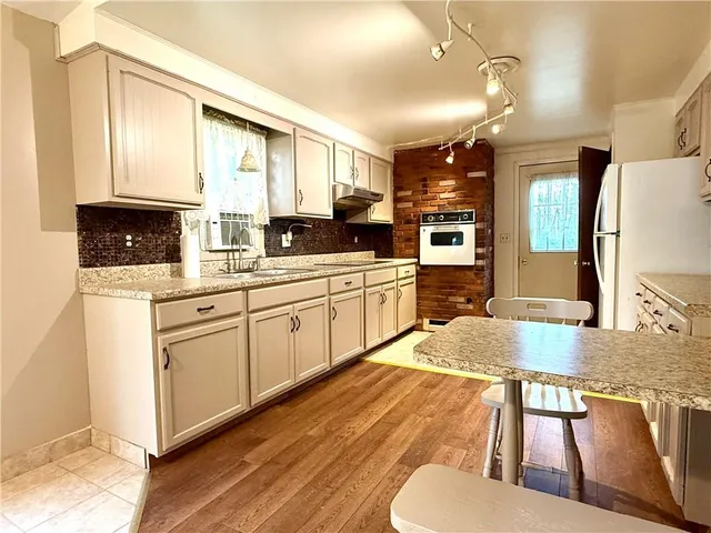 a kitchen with stainless steel appliances granite countertop a stove a sink dishwasher and a microwave oven with white cabinets