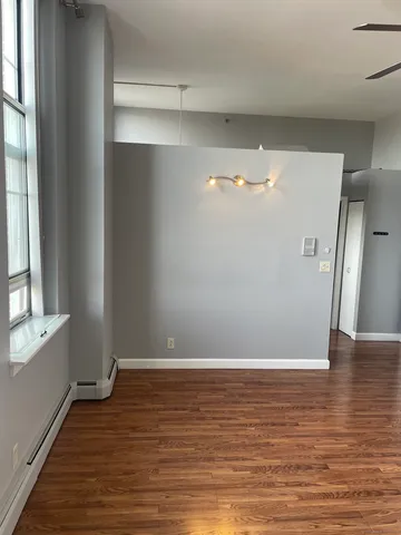 a view of an empty room with wooden floor and a window