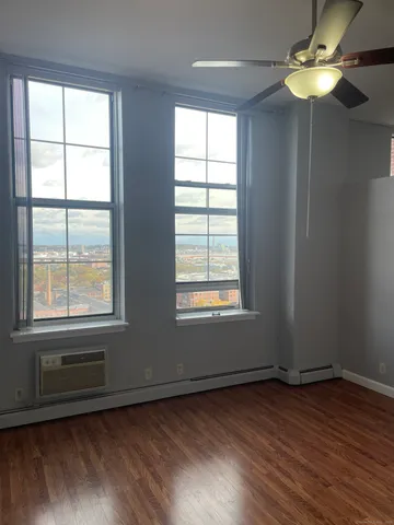 a view of an empty room with wooden floor and a window