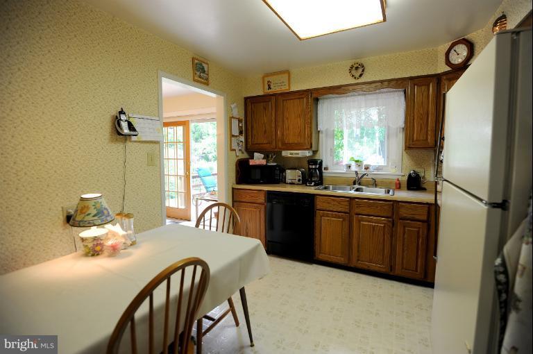 6505 Divine Street McLean, VA 22101 - Photo 22 of 26 a kitchen with stainless steel appliances granite countertop a sink a stove a refrigerator with a dining table and chairs